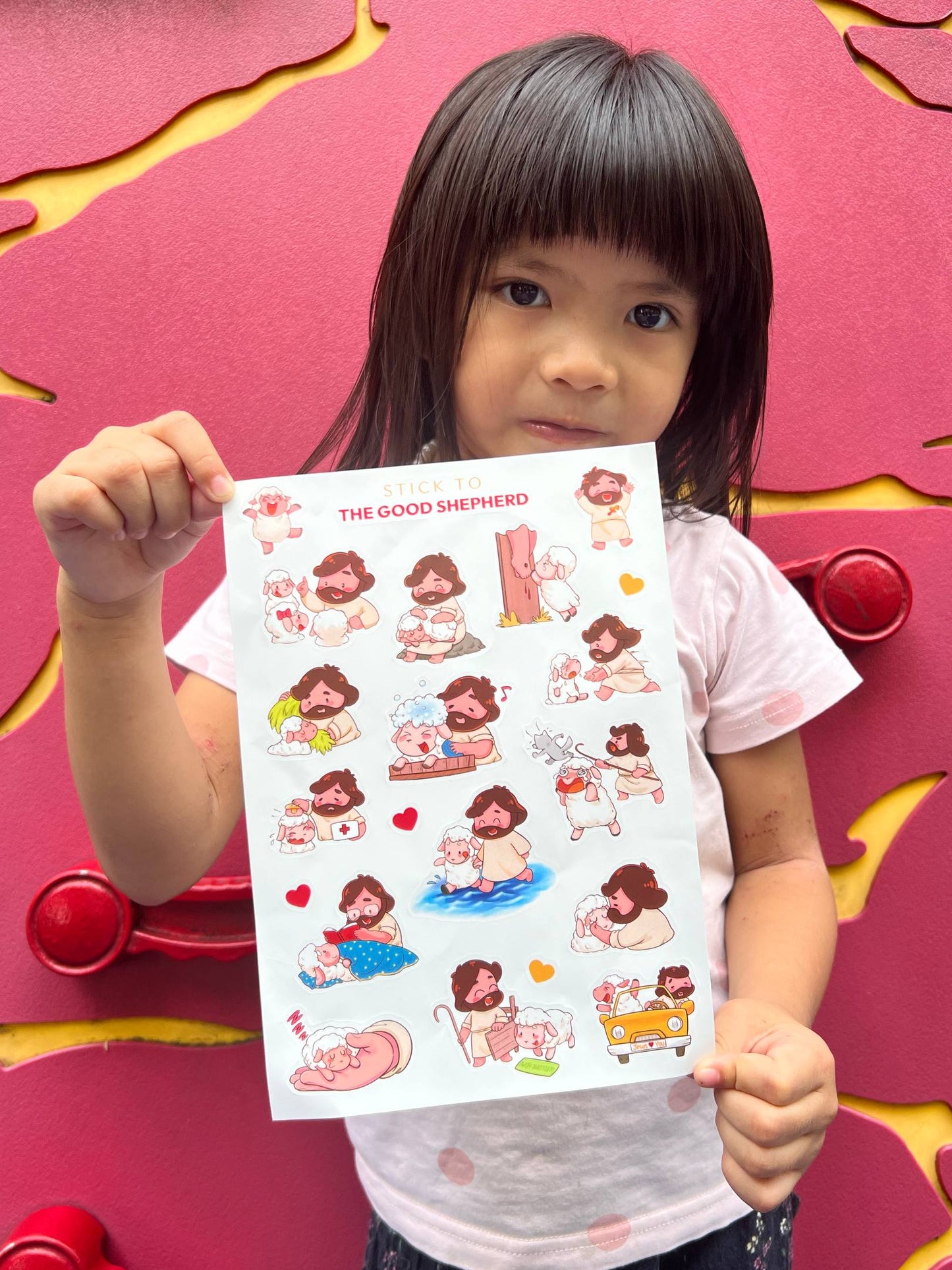 Child holding a sheet of illustrated stickers in front of a colorful background